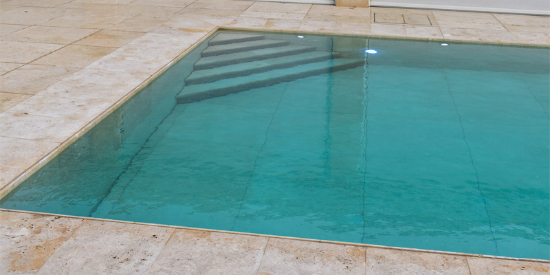 Interior de piscina con fondo móvil tieleman en piedra natural