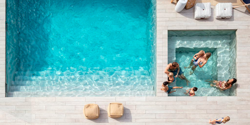 Vista dron de una familia jugando en una piscina y un spa, con suelo móvil Akvo Spiralift